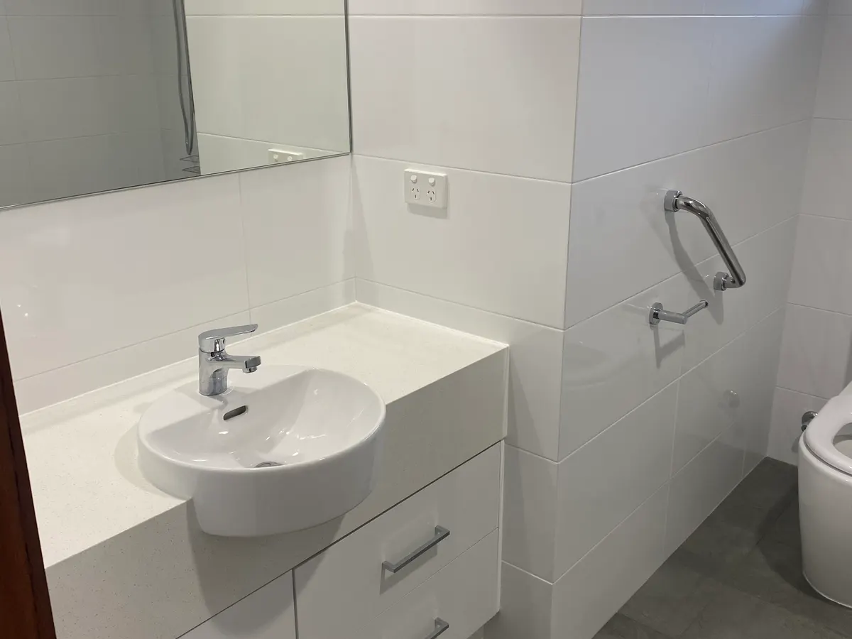 After: the rebuilt Bull Creek bathroom with a custom vanity, a grab rail beside the new toilet and non-slip floor tiles