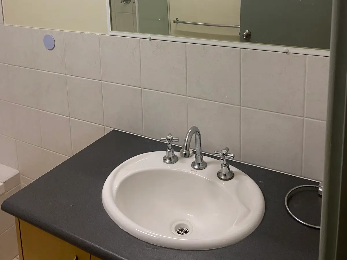 Before: the old Midland vanity with a dark benchtop, an inset basin and small square wall tiles