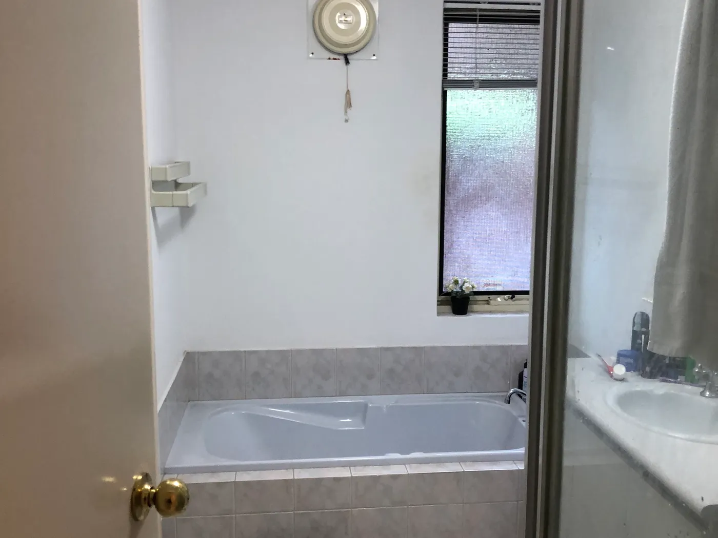 Before: the same Perth bathroom with a step-over bath under the window, a framed shower screen and no level access