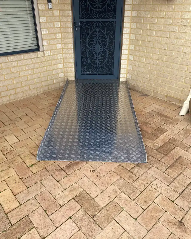An aluminium ramp with a non-slip chequer plate surface leading up to a front door over brick paving in Perth