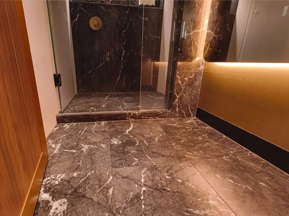 A dark marble walk-in shower and bathroom floor treated with a clear non-slip coating