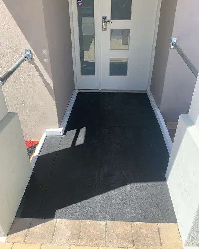 A black non-slip ramp up to a front door in Rivervale, Perth, with handrails fixed to the walls on both sides