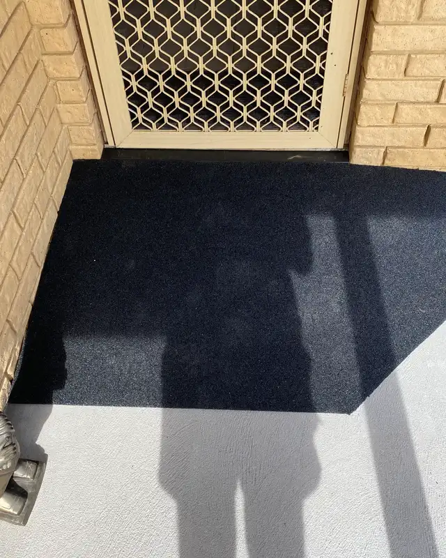 A black rubber threshold ramp with angled side wings at a back door with a security screen in a Perth home