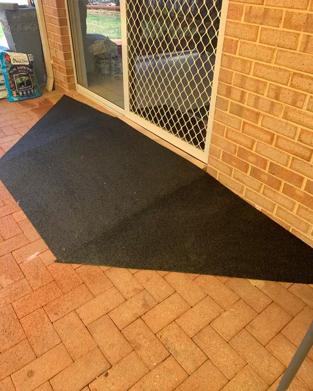 A black rubber ramp with angled wings across a sliding door threshold onto brick paving in a Perth home